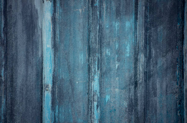 Faded blue paint is pictured on a tin building, creating a grungy, textured backdrop perfect for industrial photos or portraits.