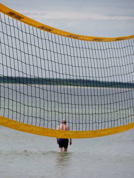 istock Man in the baltic sea behind a volleyball-net 2164112585