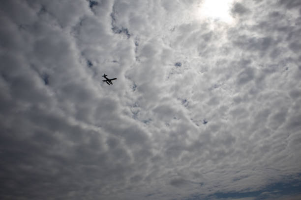 istock An airplane crosses a mottled cloudy sky 2164124488