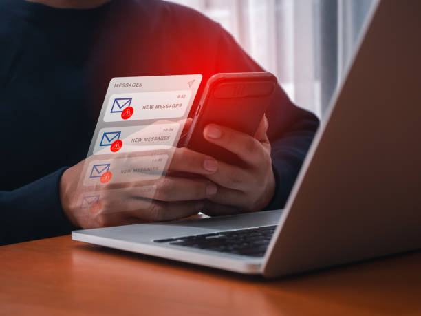 istock SMS spam and fake text message phishing concept. System hacked warning alert, email hack, scam malware spreading virus on messages alert showing on mobile smartphone in businessman hand at workplace. 2164130694
