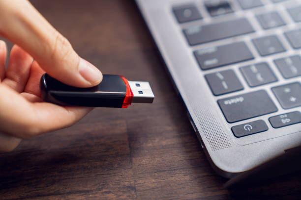 istock Hand holding usb flash drive with connecting to laptop at wooden table 2164136741
