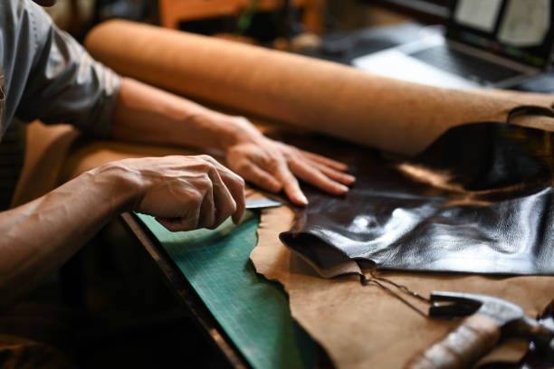 istock Close up view of craftsman skillfully using a cutting tool to shape the leather 2164136862