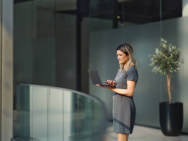 istock Smiling businesswoman using laptop in a hallway. 2164142050