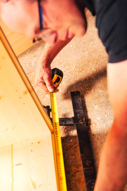 istock Carpenter measuring wooden plank using tape measure in workshop 2164142436