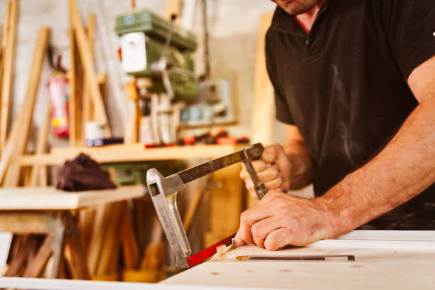 istock Carpenter using a hacksaw to cut wood in workshop 2164142520