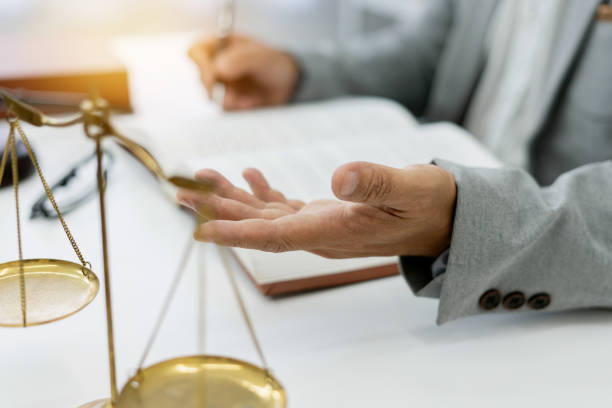 il consulente legale freelance assiste il cliente in una causa, discutendo piani e diritti concentrandosi sull'onestà e l'integrità, con libri e bilance legali a portata di mano in un ambiente professionale. - difesa legale foto e immagini stock