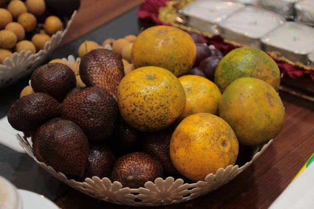 some fruits such as oranges, snake fruit and longan fruit in a plastic basket as a dessert