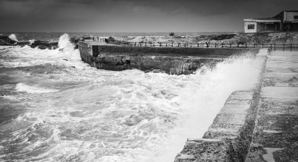 Stormy coastal landscape with stone fortifications and breaking waves