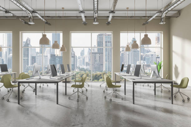istock An open-plan office with modern furniture and computers placed near large windows overlooking a city skyline, bright workspace, concept of contemporary office interior.  3D Rendering 2164146981