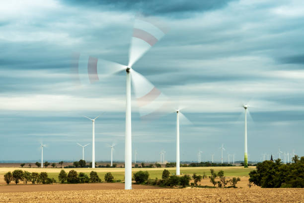 Wind Turbines rotating in empty field, Stormy Sky with Clouds above, long exposure