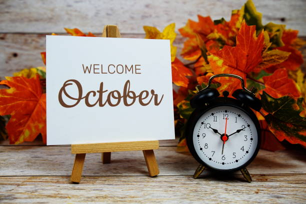 istock Welcome October text with alarm clock and maple leaf decoration on wooden background 2164154304