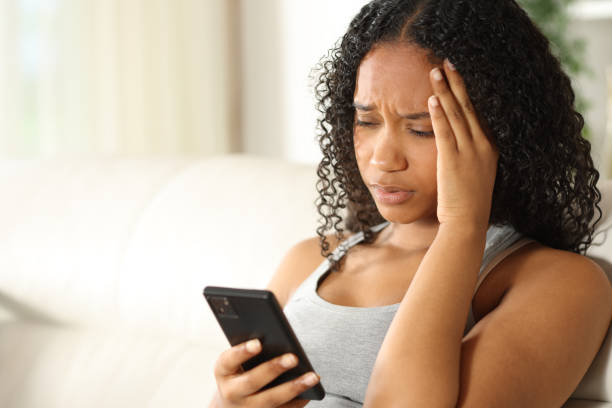 istock Worried black woman checking phone at home 2164155683