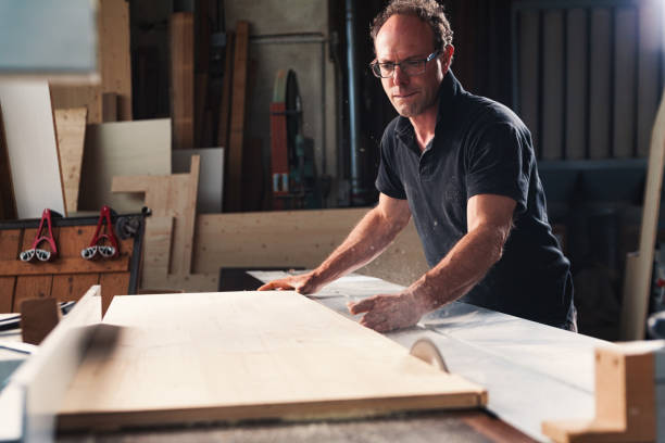 istock Carpenter cutting wood plank using circular saw in workshop 2164155840