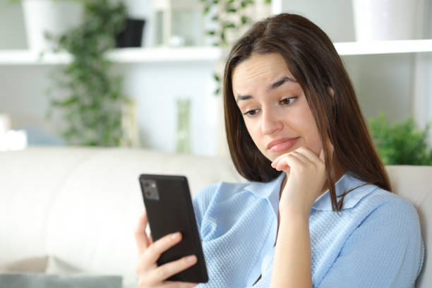 istock Disappointed woman checking cell phone at home 2164156022