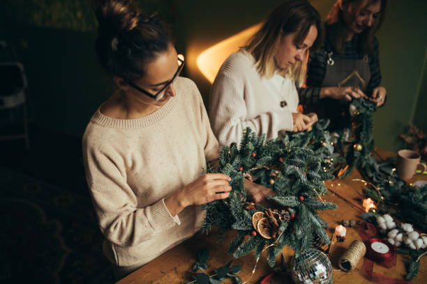 istock Happy women making Christmas wreath using natural pine branches and festive decorations. 2164157627