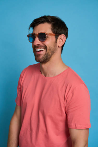 istock Handsome man wearing sunglasses is laughing on blue background 2164162267