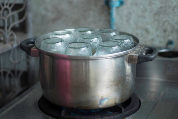 Sterilization bottles by aluminium steamer on the gas stove in kitchen closed up selective focus blur background.