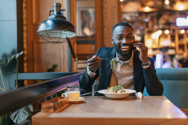 istock Smiling man on phone eating pasta in a restaurant. 2164166296