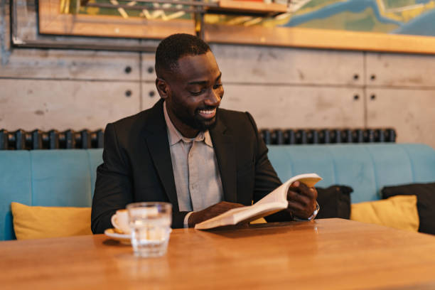 istock Smiling man enjoying a book in charming cafe. 2164166379