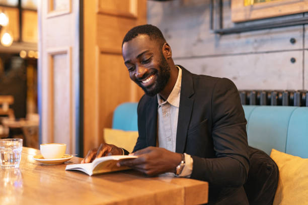 istock Man in suit reading book with coffee in cafe 2164166389