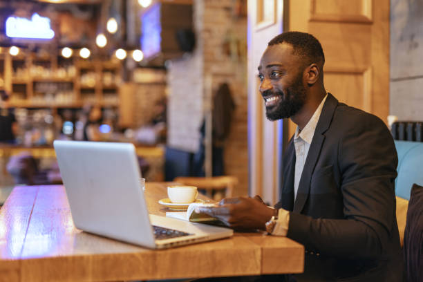 istock Man reading book with laptop in cozy, stylish cafe. 2164166431