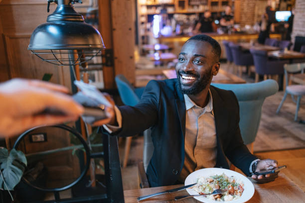 istock Man happily paying bill at restaurant table 2164166620