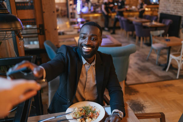 istock Happy man with credit card in restaurant setting 2164166659