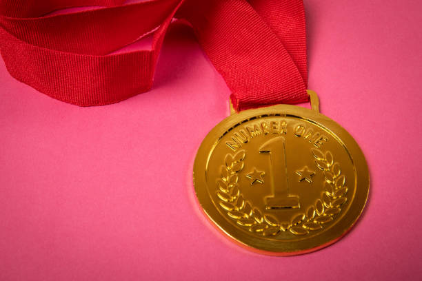 Gold medal with red ribbon on pink background.