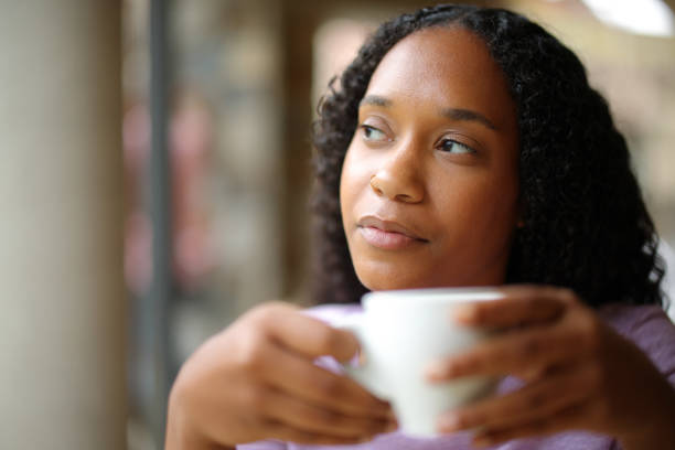 istock Pensive serious black woman drinking coffee looking at side 2164169715