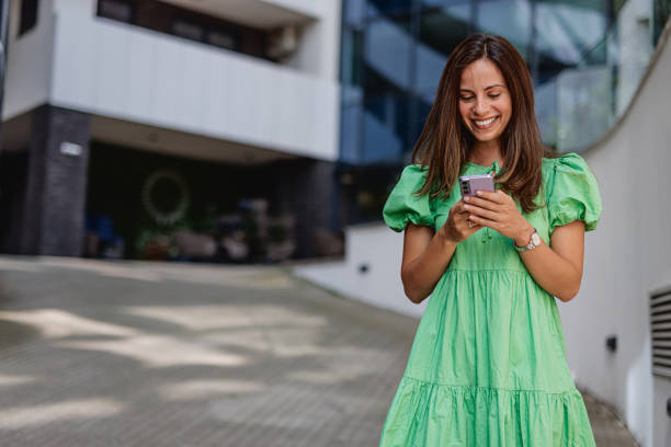 istock Woman Smiling While Texting on Mobile Phone 2164179168