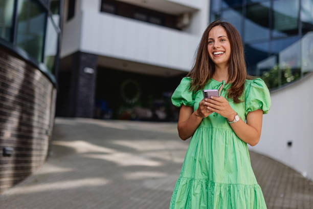 istock Beautiful Woman Smiling While Holding  Mobile Phone 2164179326