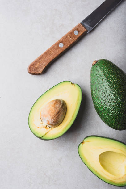 istock Whole and halved avocados with knife on light background 2164182624