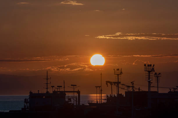 Beautiful Sunset at the busy port showing silhouette of crane.