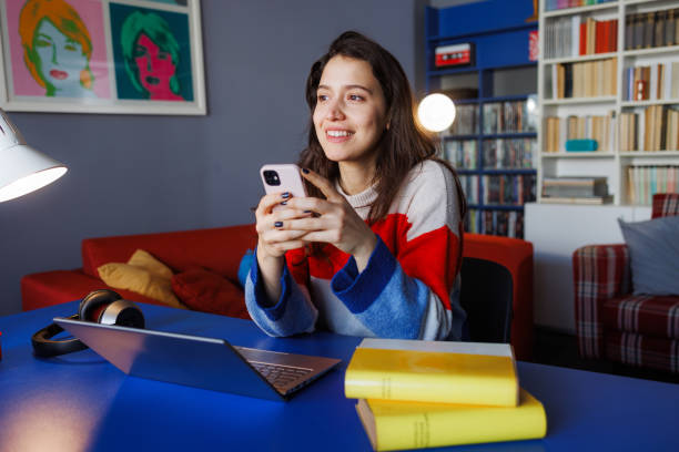 istock Happy woman using smart phone while studying at home 2164184364