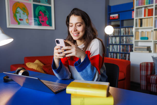 Woman smiling while using smart phone in cozy home office