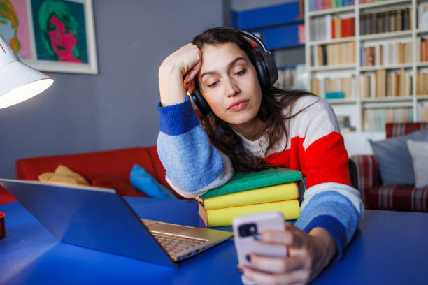 Young woman with headphones distracted while studying at home