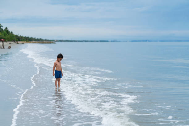 Latino boy from Cartagena Colombia, between 4 and 5 years old;  walking alone on the beach during a beautiful morning