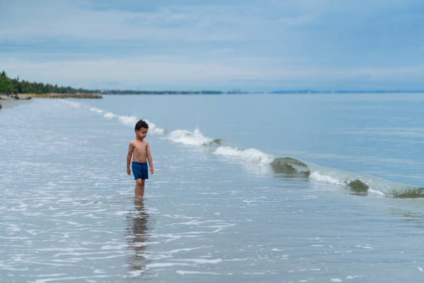 Latino boy from Cartagena Colombia, between 4 and 5 years old;  walking alone on the beach during a beautiful morning