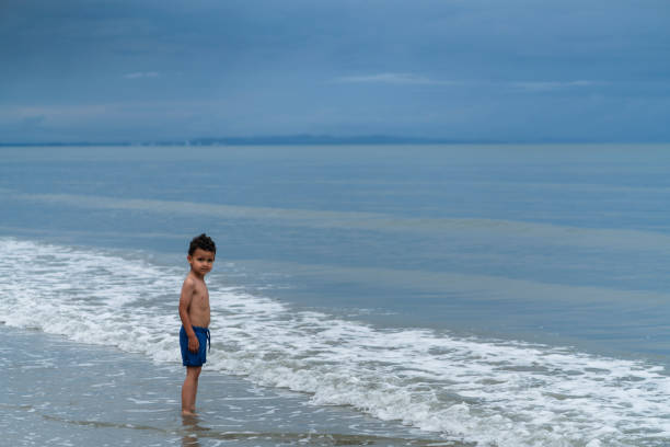 istock boy walking on the beach alone during a beautiful morning 2164187812