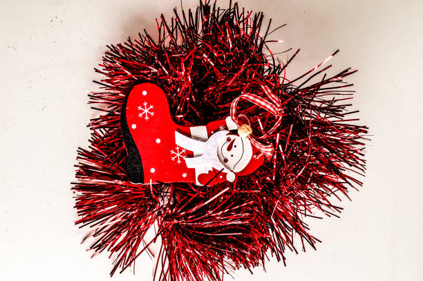 A red christmas ornament with a white face and red boot