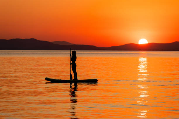 istock Young woman floating on paddle board at sunset 2164188525