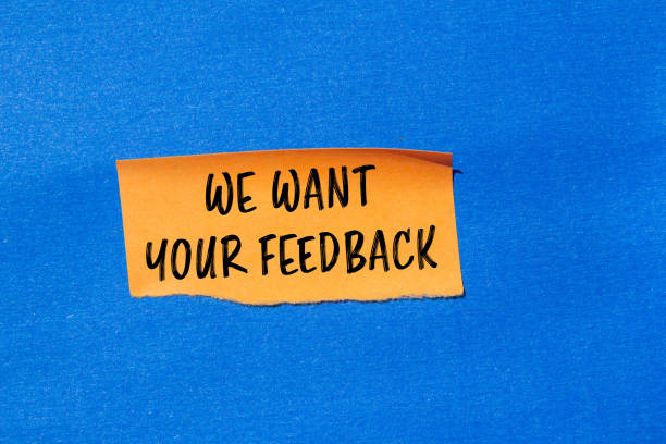 istock We want your feedback message written on ripped torn orange paper piece with blue background 2164189520