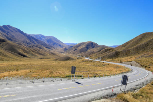 Lindis Pass, an unusual view with tussocks cover mountain. The color blue sky contrasts with the yellow of grassland.