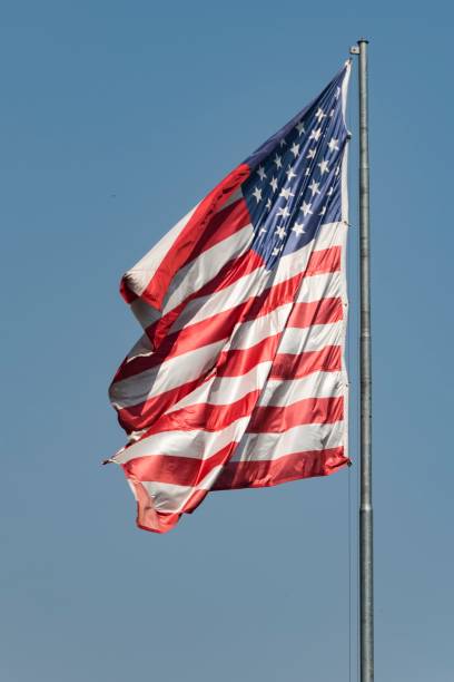istock American flag flying on the flagpole. Blue sky background. 2164216016
