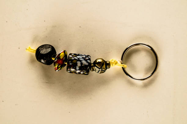 A key chain made of beads and a gold ring. The beads are of different colors and sizes