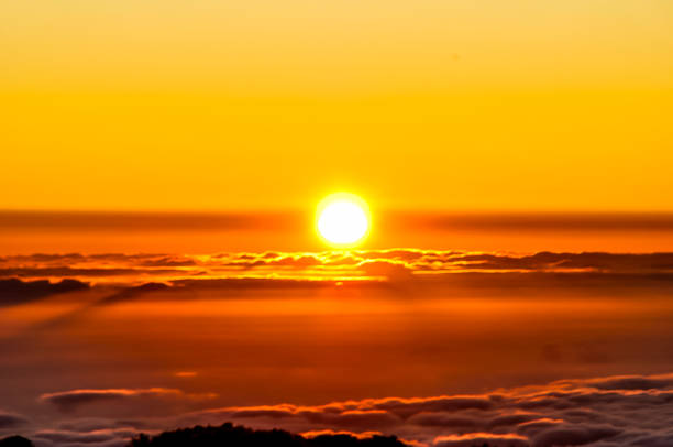 istock The sun is setting in the sky, casting a warm orange glow over the clouds 2164224117