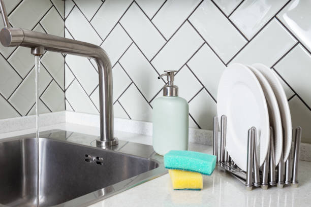 istock Modern Clean Kitchen Sink with Running Water and clean white plates 2164232403