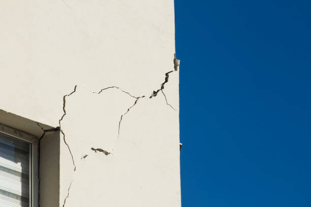 Close-up taken of apartment wall cracked due to severe earthquake on blue background with copy space