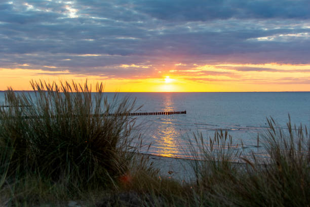 istock Sunset over the sea, with sand dunes and blurred beach grass 2164248900