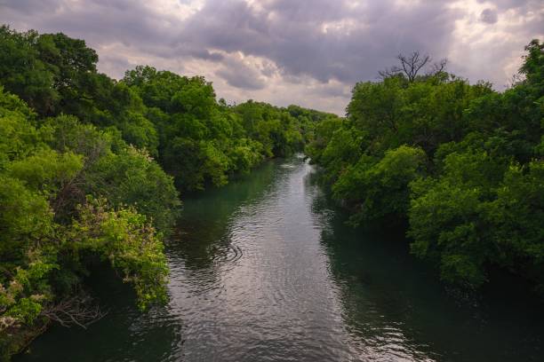 istock Serene river flowing through lush green forest under a cloudy sky in Zilker Park, Austin, Texas 2164249258